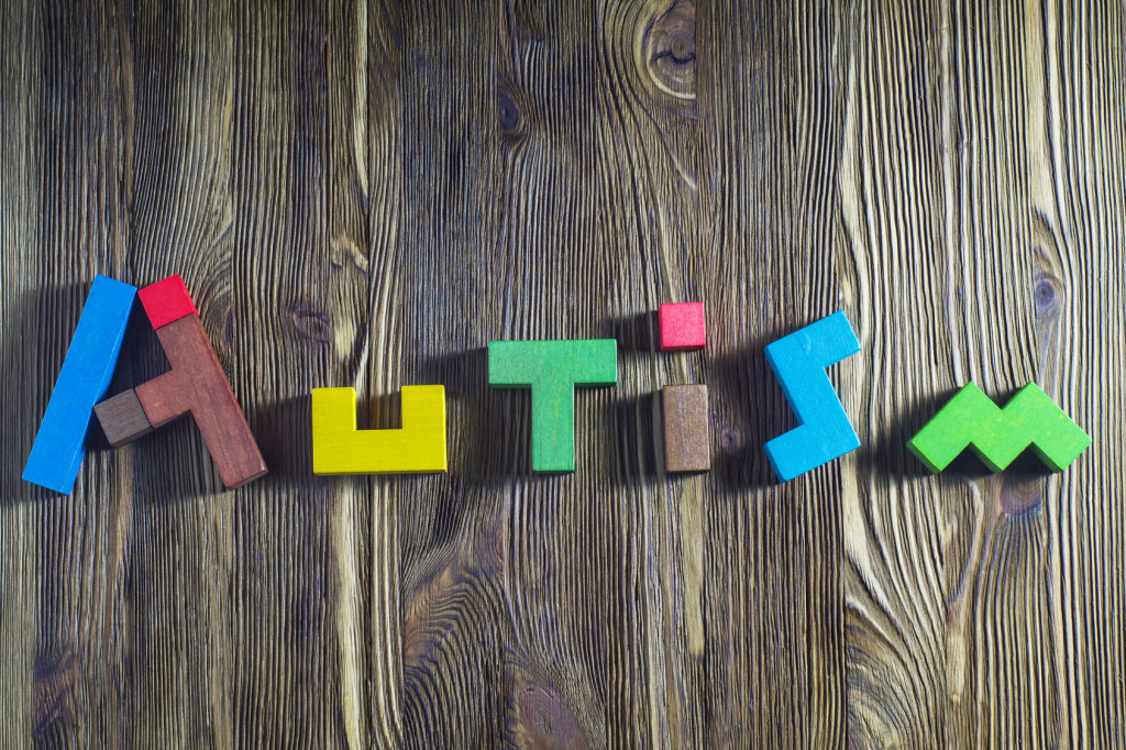 Autism awareness month. Word Autism built of wooden puzzles on a wooden background. Concept of autism word.