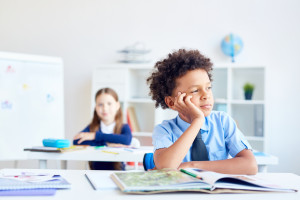 How to support a child who is a gifted underachiever. Child day dreaming in a classroom.